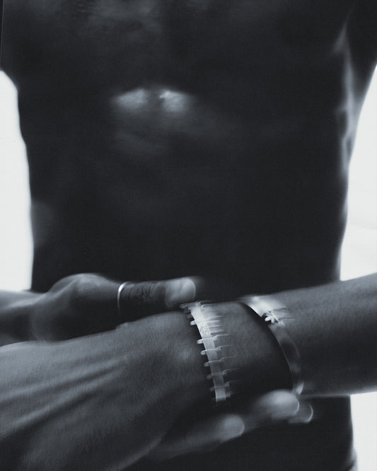 Modelin bileğinde arka planda görünen Two-Borg Toxic Bracelet, oksitli gümüş yüzeyi ve kırık logo detayıyla